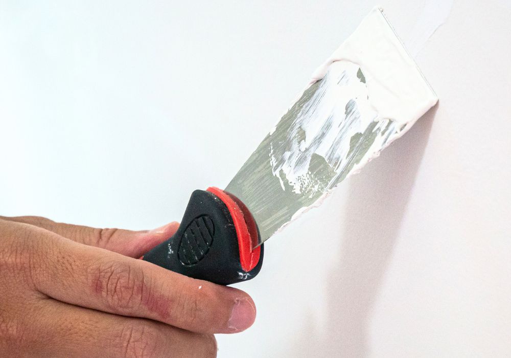 Espátula y masilla para reparar grietas antes de pintar.